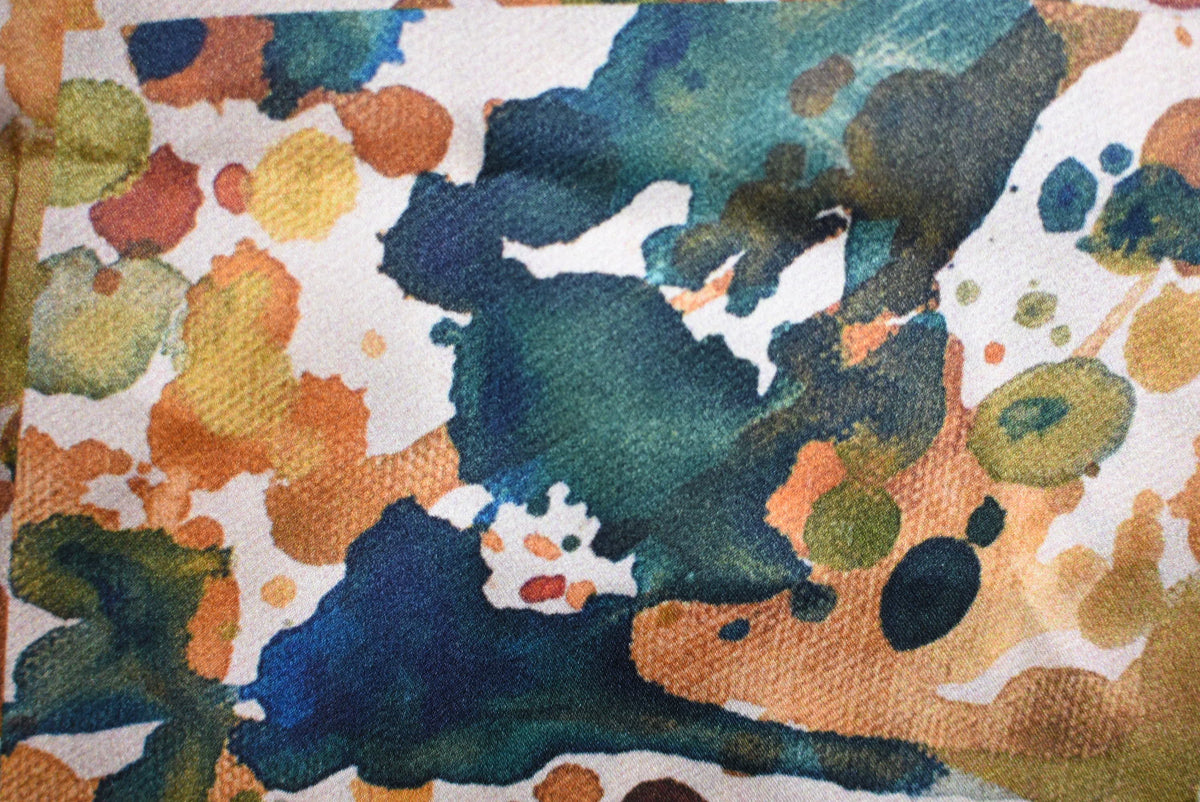 Abstract art with splashes of blue, green, orange, and white on a textured surface.