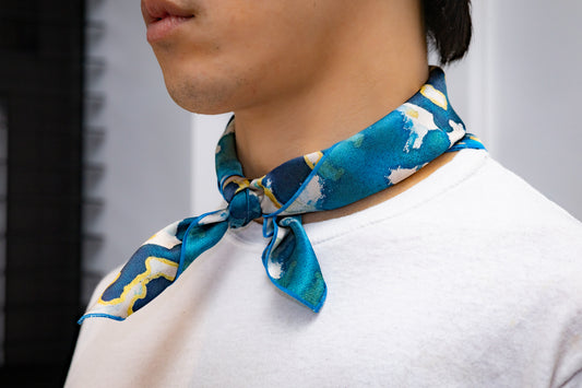 Person wearing a blue patterned scarf around their neck with a blurred background