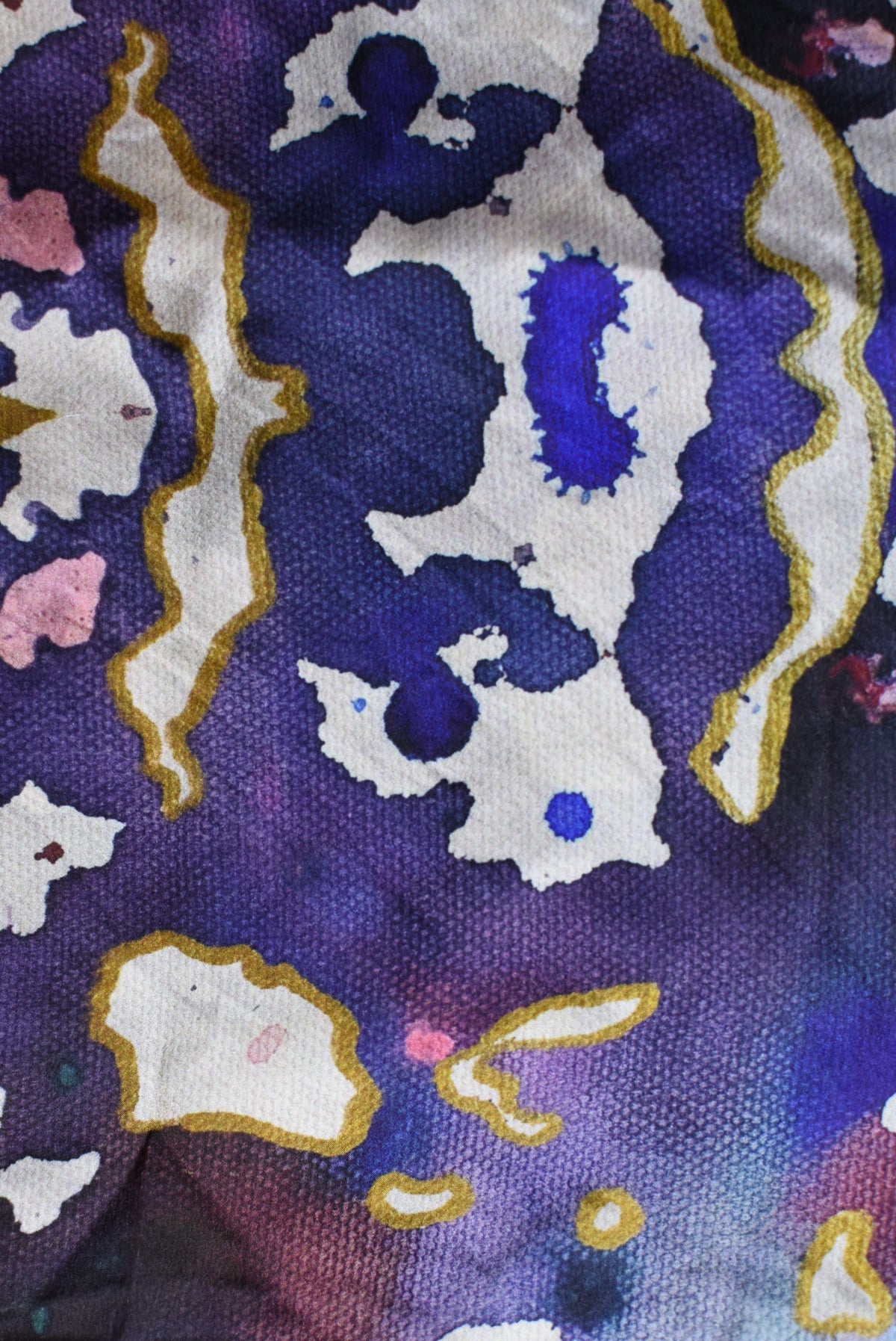 Close-up of fabric with abstract pattern featuring animals and geometric shapes on a purple background.