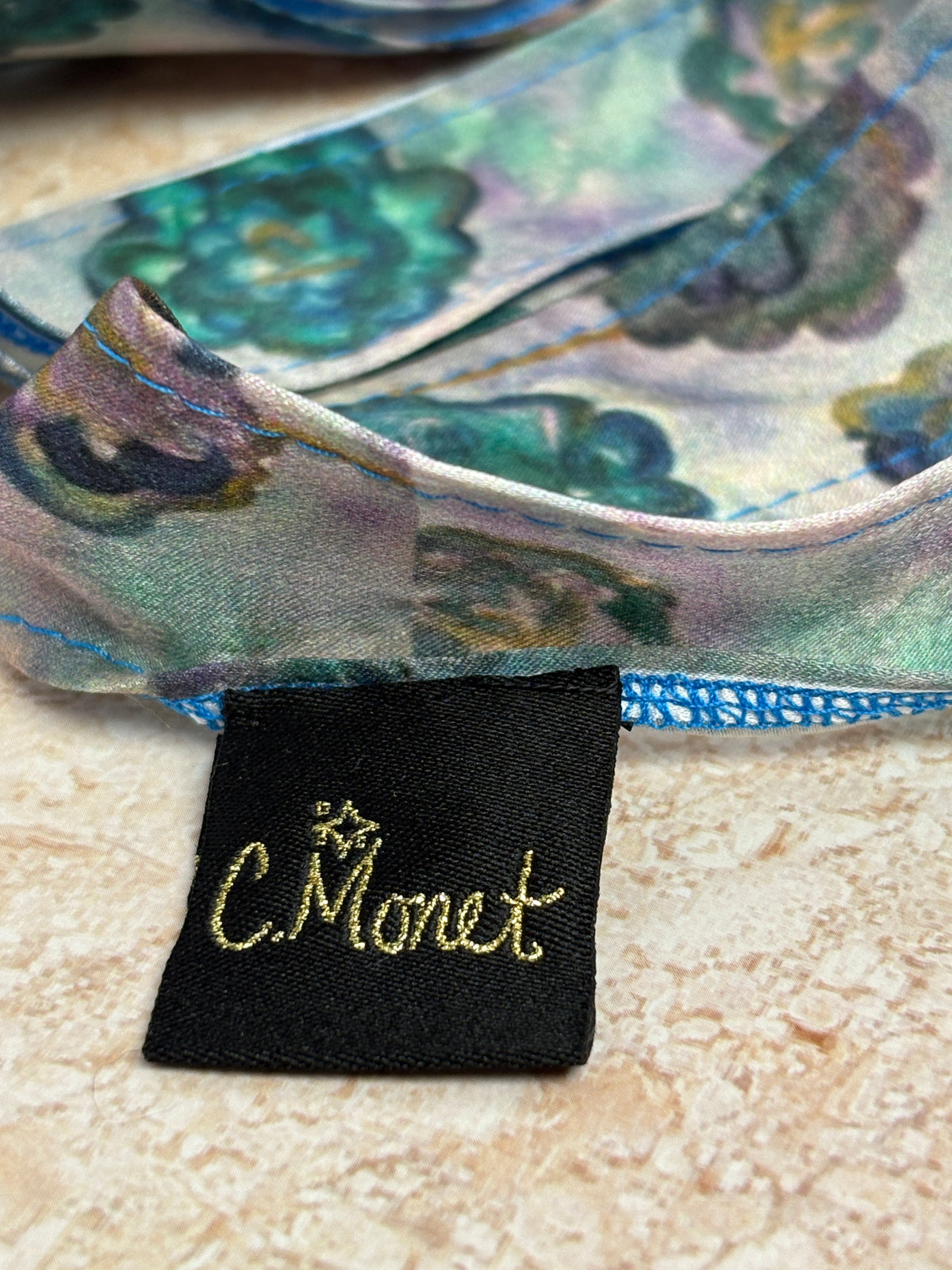 Close-up of a Monet label on a decorative item with floral patterns.