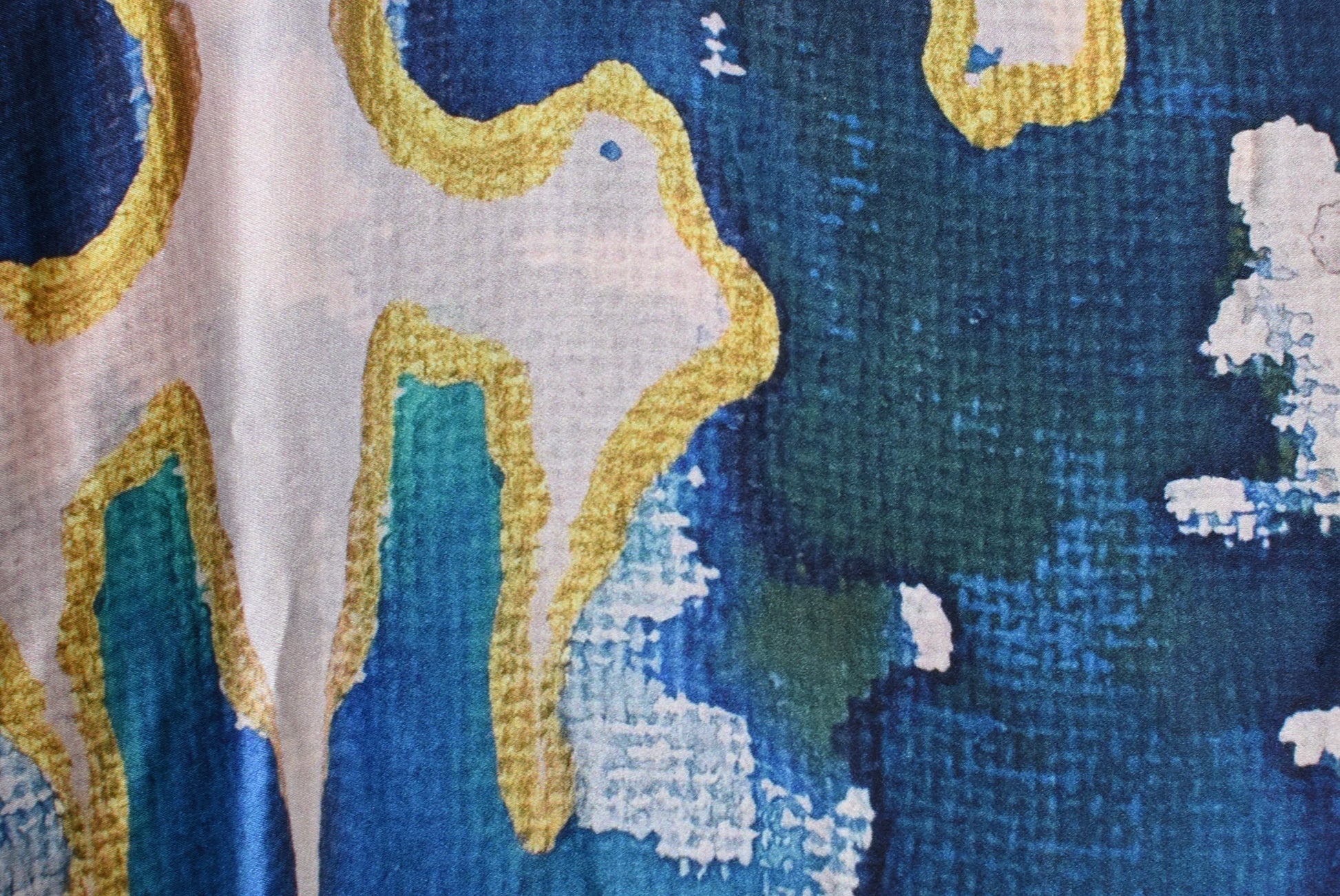 Close-up of a cross-stitched piece with blue, green, and yellow patterns.