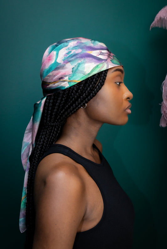 Woman wearing a colorful headscarf against a dark green background
