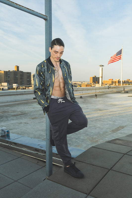 Man leaning against a railing on a rooftop with a cityscape