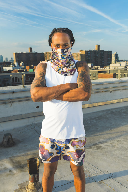 Person wearing a white tank top and colorful shorts on a rooftop with cityscape in the background