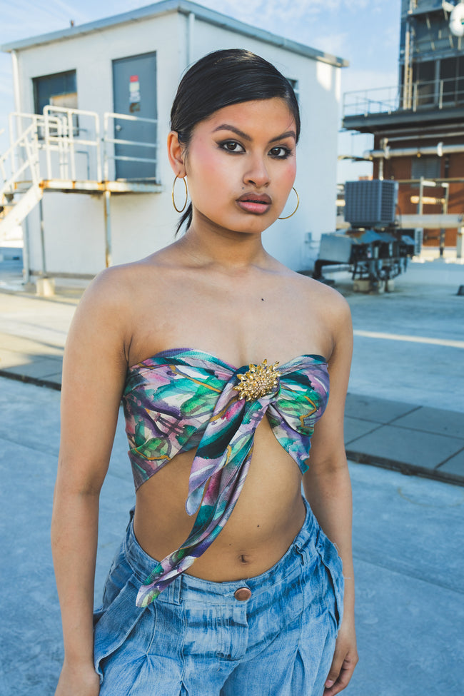 Woman wearing a floral top and denim pants in an urban setting
