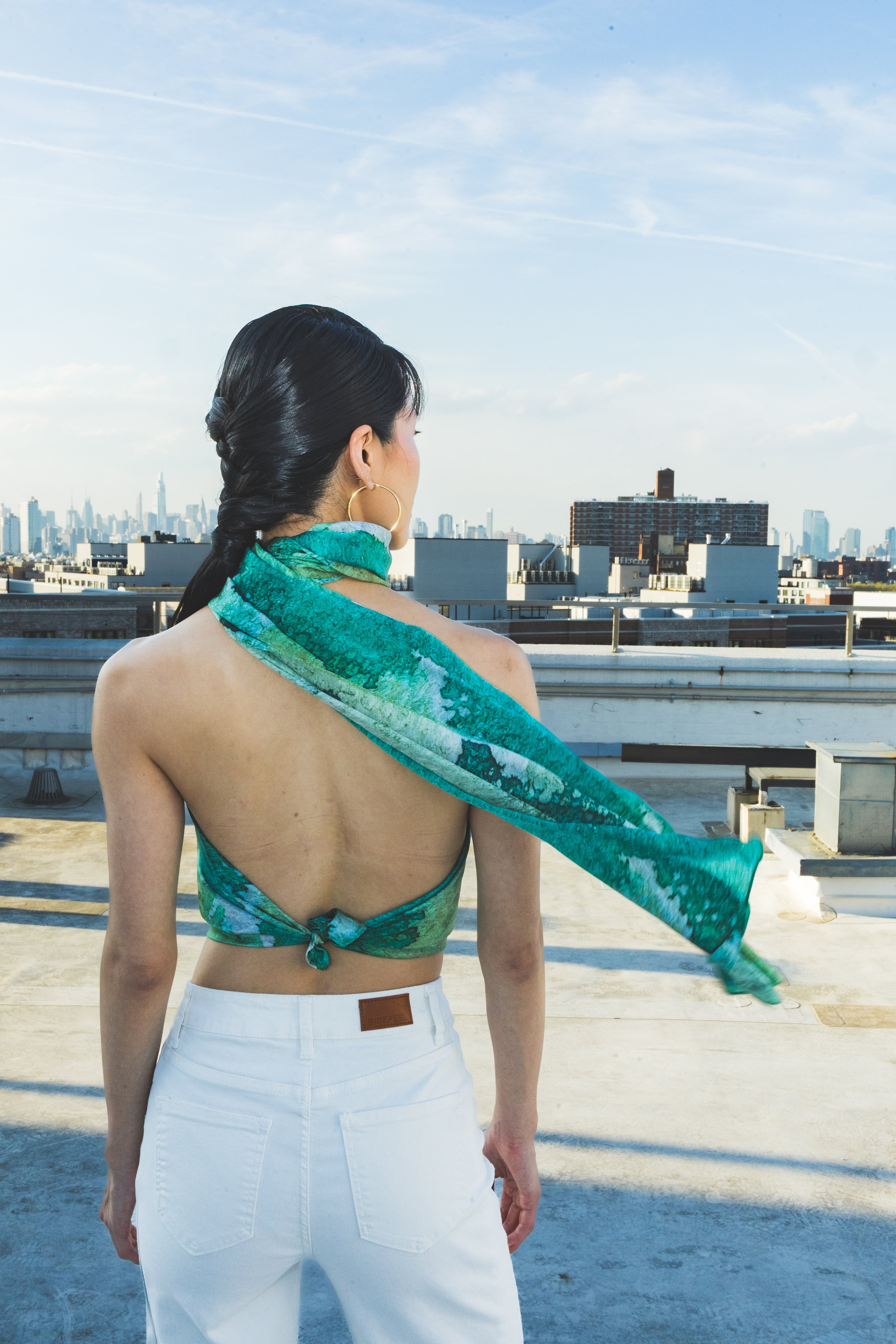 Woman on a rooftop wearing a green patterned top and white pants
