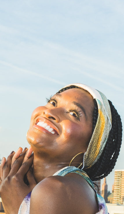 Woman with a headscarf looking up towards the sky with buildings in the background