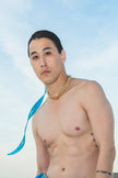 Man wearing a blue tie-dye towel around his waist on a rooftop
