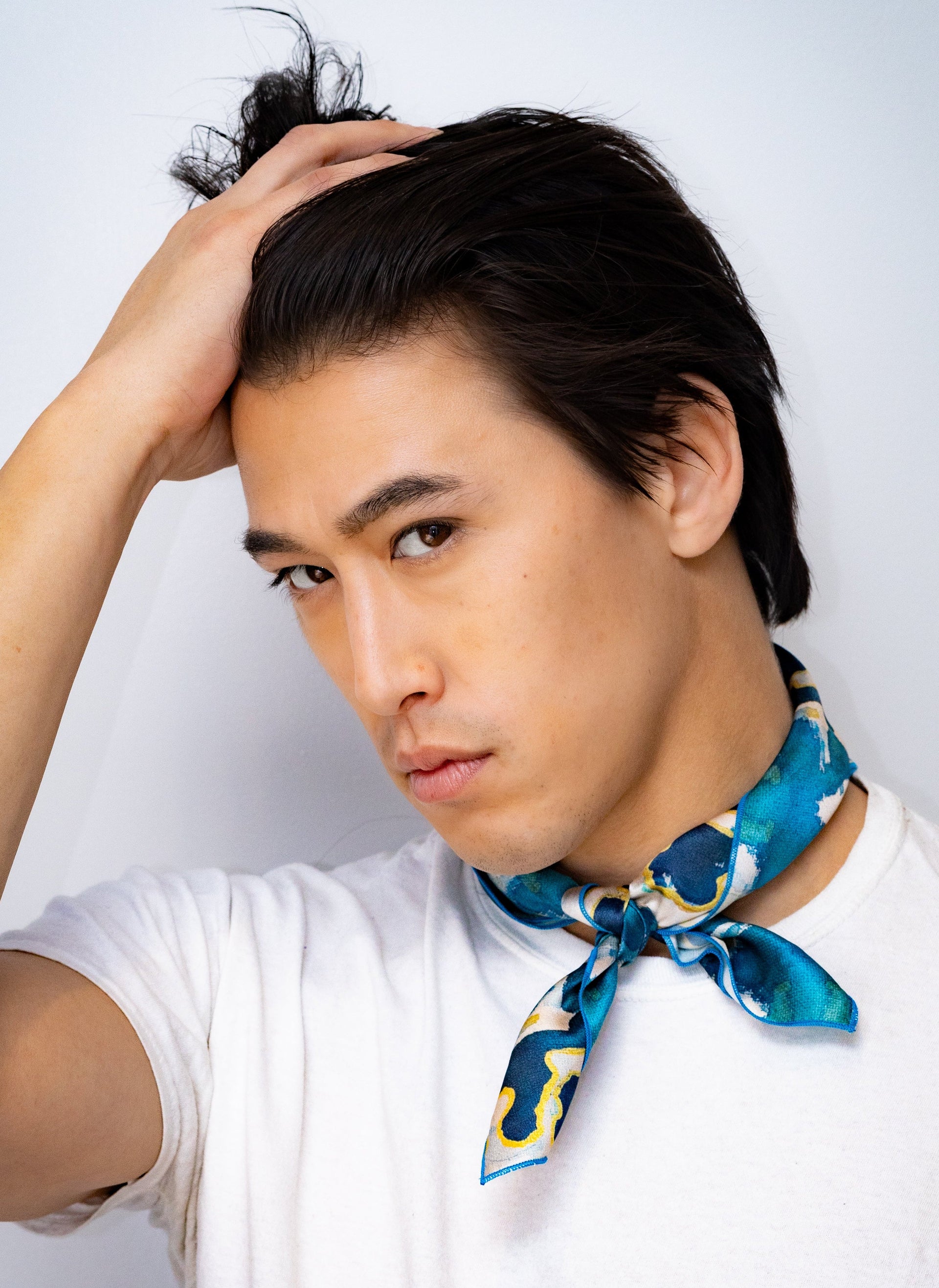 Man wearing a white shirt and blue patterned scarf 