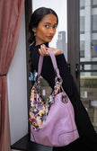 Woman holding a large pink handbag with a floral patterned strap.
