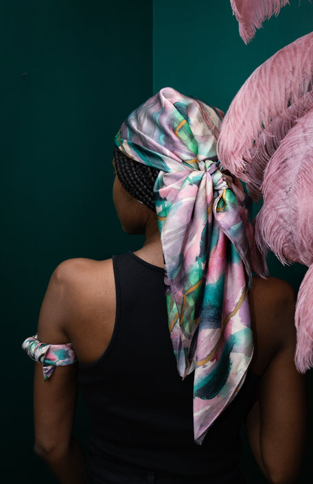 Person wearing a colorful headscarf with pink feathers