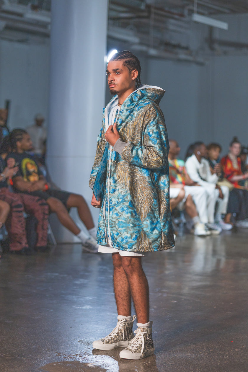 Model walking on a runway wearing a patterned outfit 