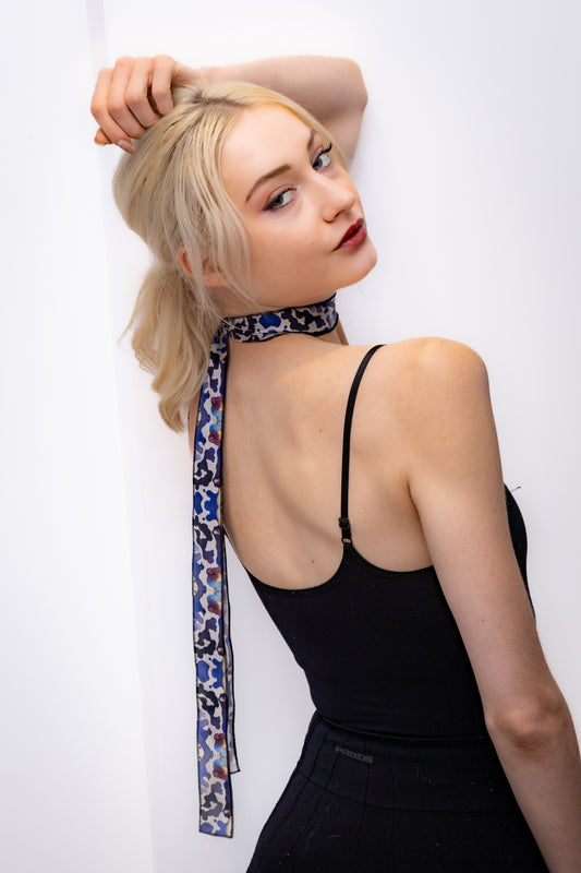 Woman wearing a black dress with a patterned scarf over her shoulder against a white background