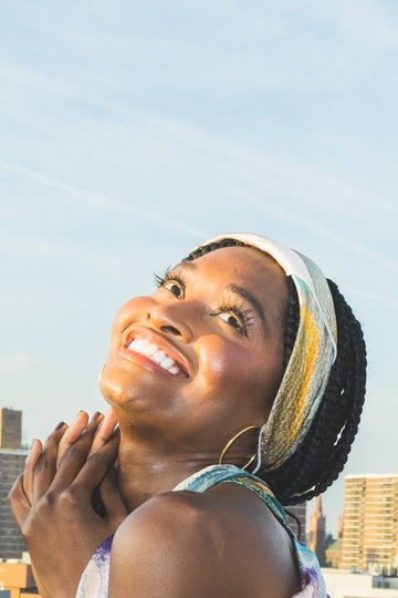 Woman with a headscarf looking up towards the sky with buildings in the background