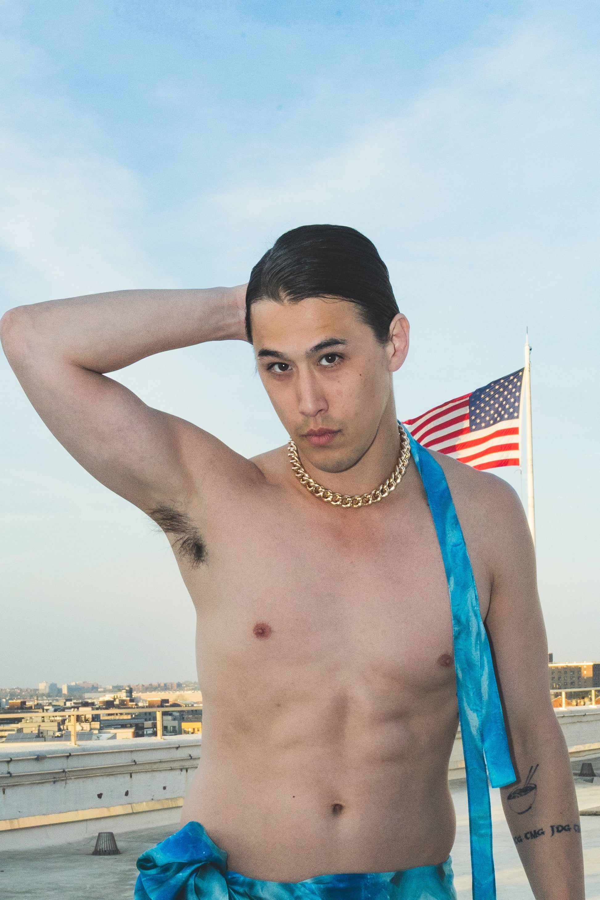 Man on a rooftop wearing a blue towel and swim shorts 