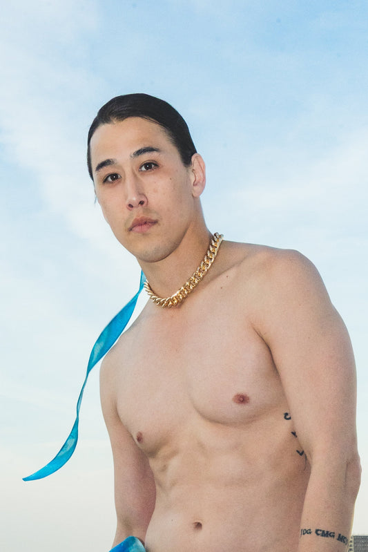 Man wearing a blue tie-dye towel around his waist on a rooftop
