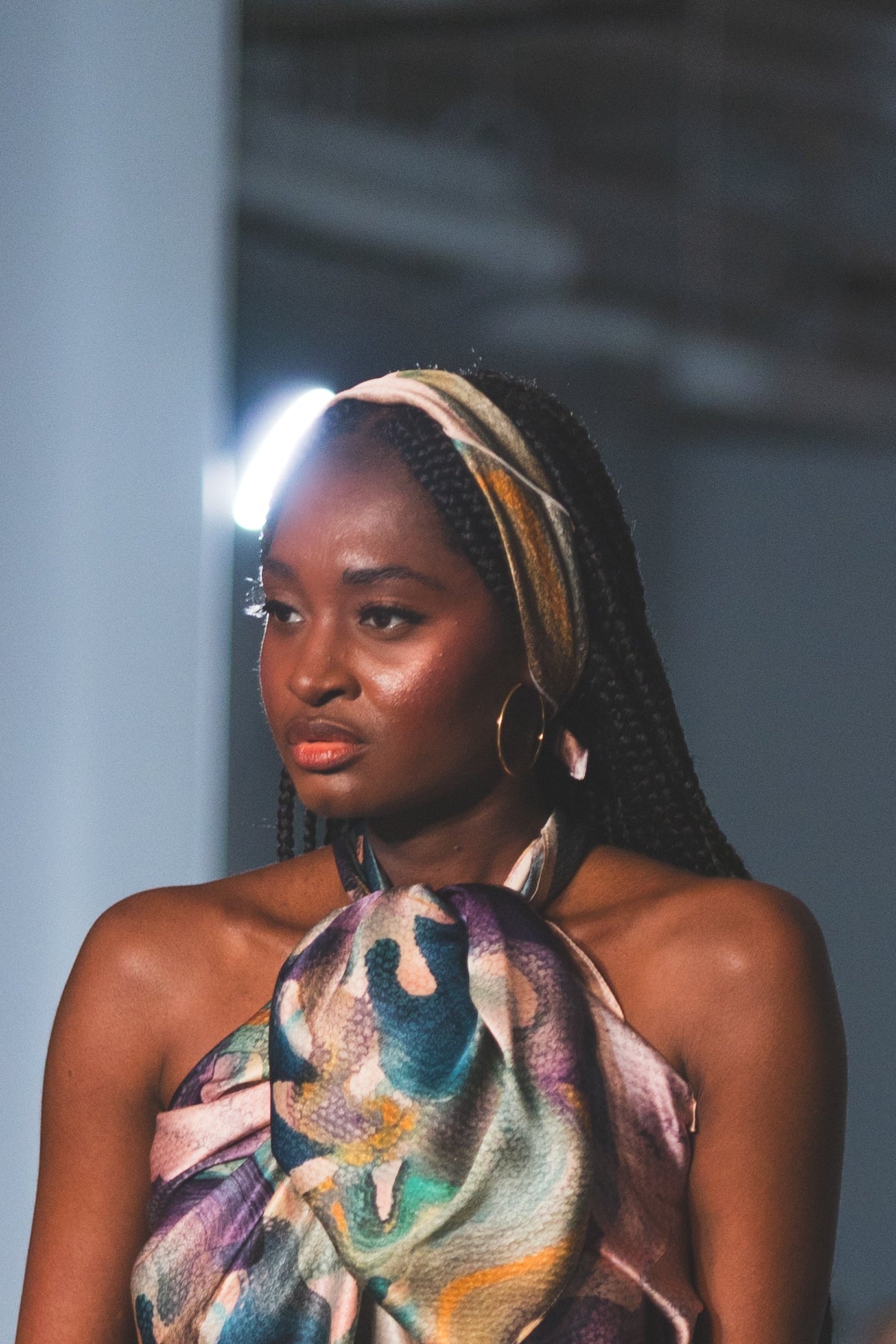 Model walking on a runway wearing a colorful dress with feather details.