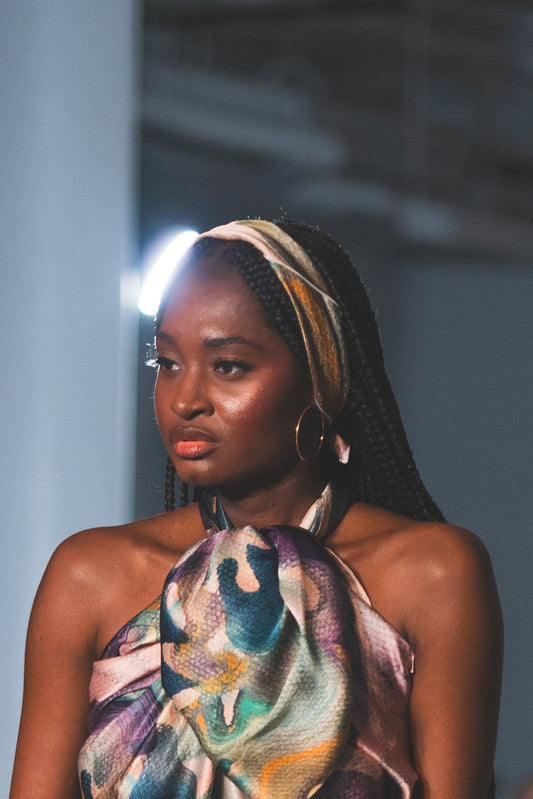 Model walking on a runway wearing a colorful dress with feather details.