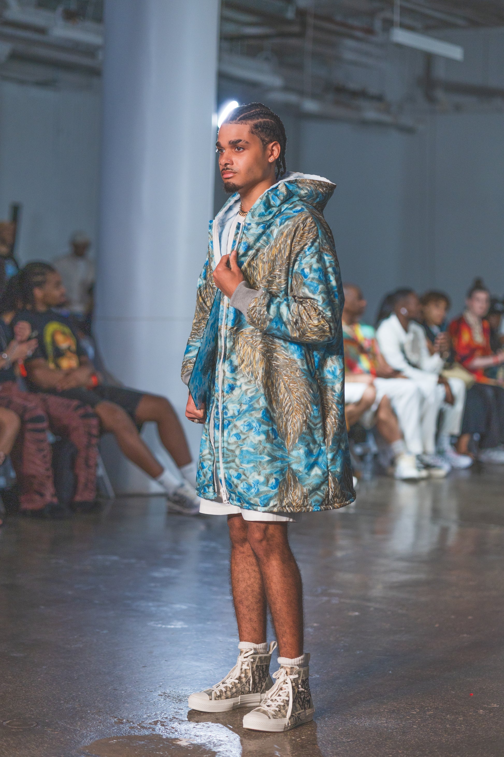 Model walking on a runway wearing a patterned outfit 