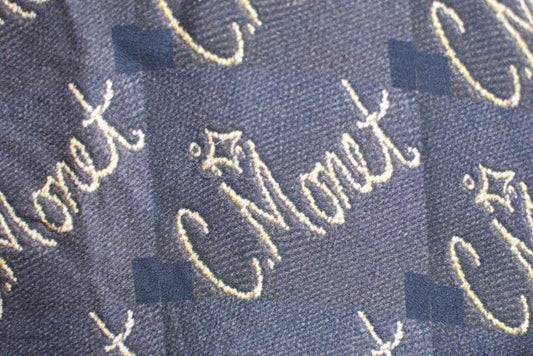 Navy fabric with embroidered 'C. Monet' text pattern