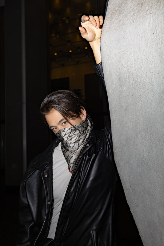 Person wearing a black coat and patterned scarf against a dark background