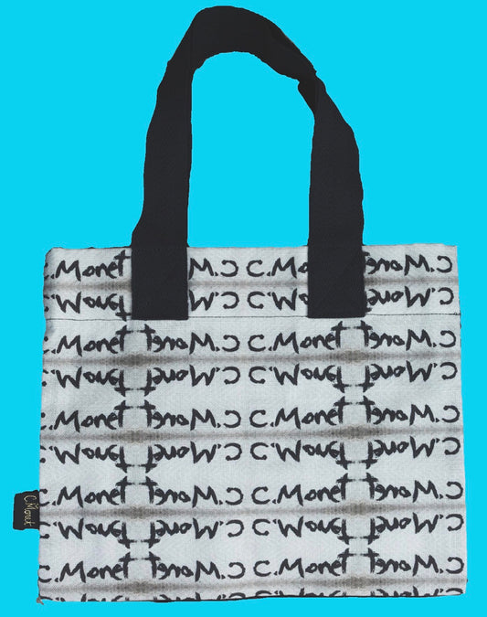 A white tote bag with black handles and a repeating black script pattern of 'C. Moret' and 'Bouclé', shown against a solid light blue background.