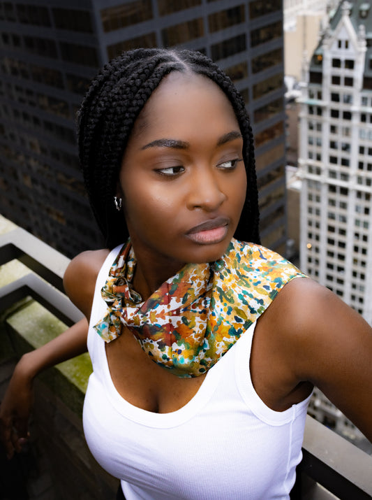 Woman with braided hair wearing a colorful scarf in an urban setting