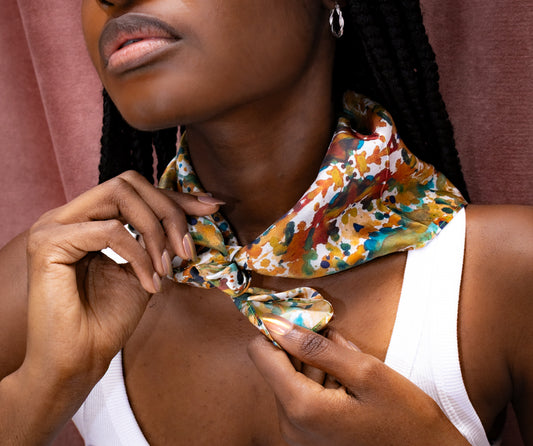 Woman wearing a colorful floral scarf with a neutral background
