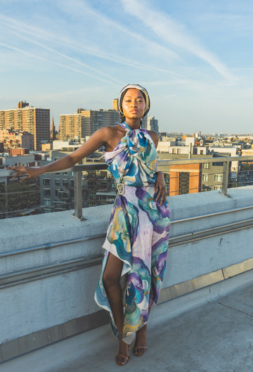 Woman in a colorful dress standing on a rooftop with cityscape in the background