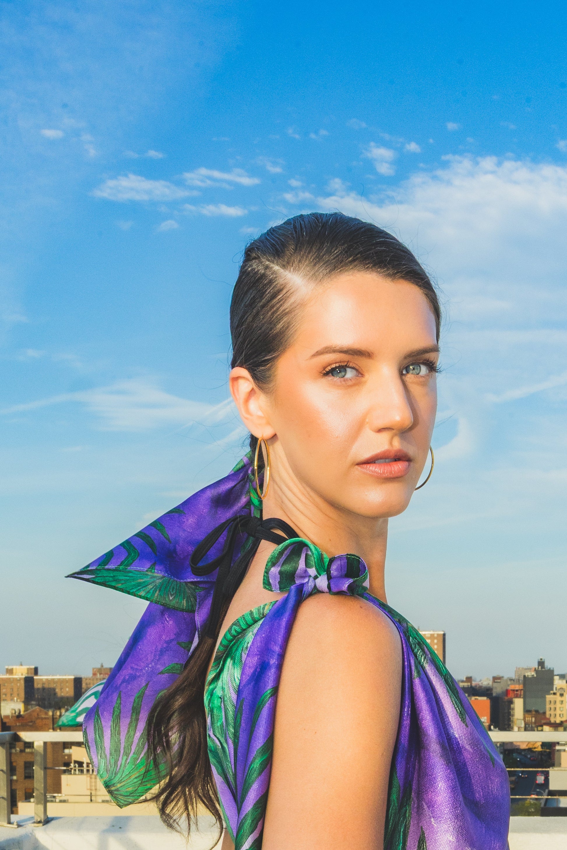 Woman in a purple dress with green leaf patterns on a rooftop