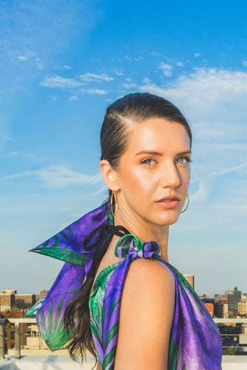 Woman in a purple dress with green leaf patterns on a rooftop
