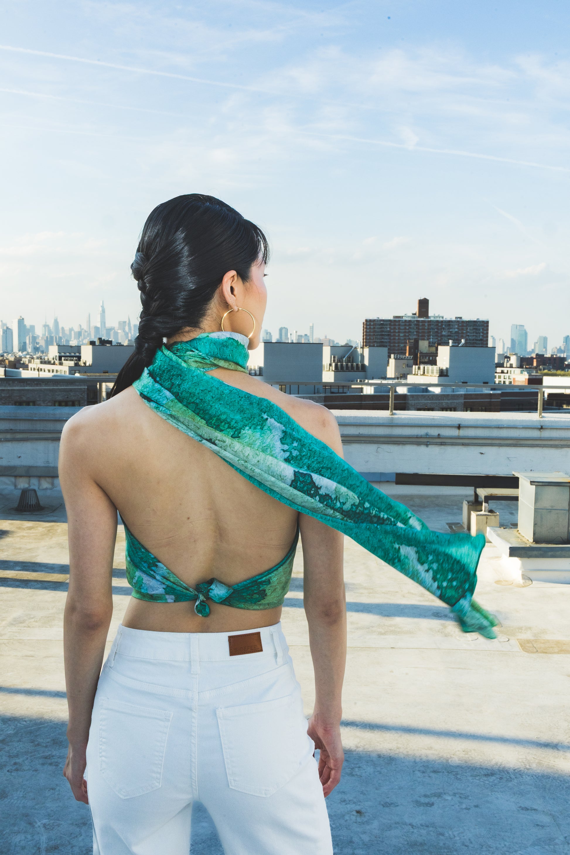 Woman on a rooftop wearing a green patterned top and white pants