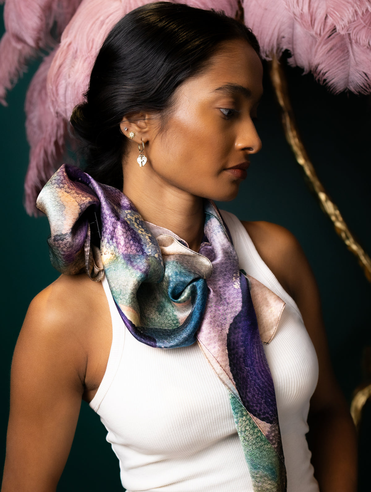 Woman wearing a colorful scarf with a feathered headdress against a dark background