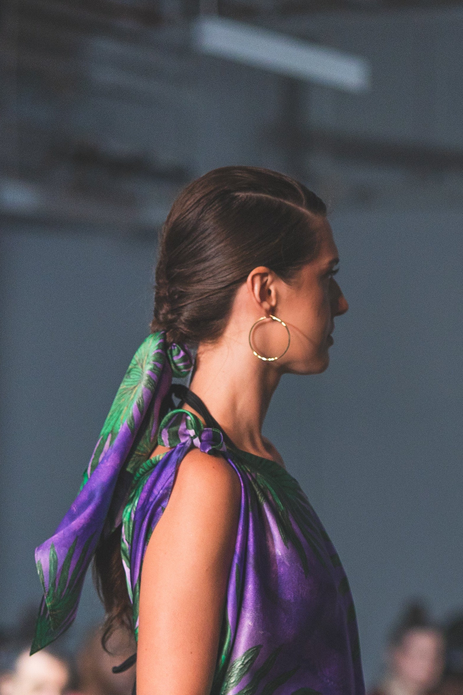 Woman wearing a purple dress with a green and purple scarf