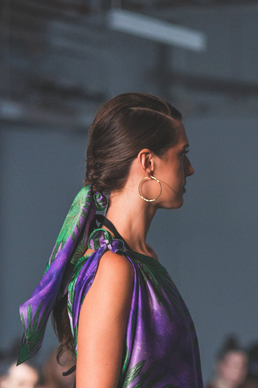Woman wearing a purple dress with a green and purple scarf