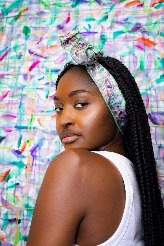 Woman with braided hair wearing a headband against a colorful abstract background