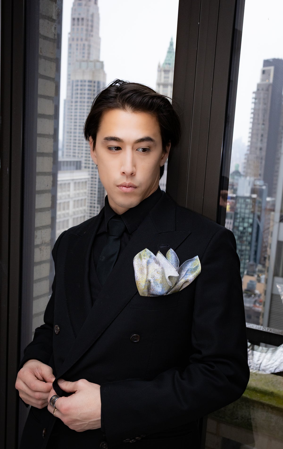 Man in a black suit with a cityscape in the background