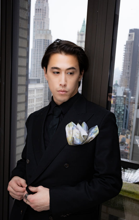 Man in a black suit with a cityscape in the background
