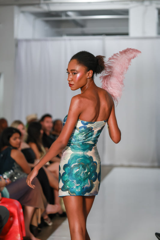 Model wearing a blue and white abstract print strapless mini dress on runway