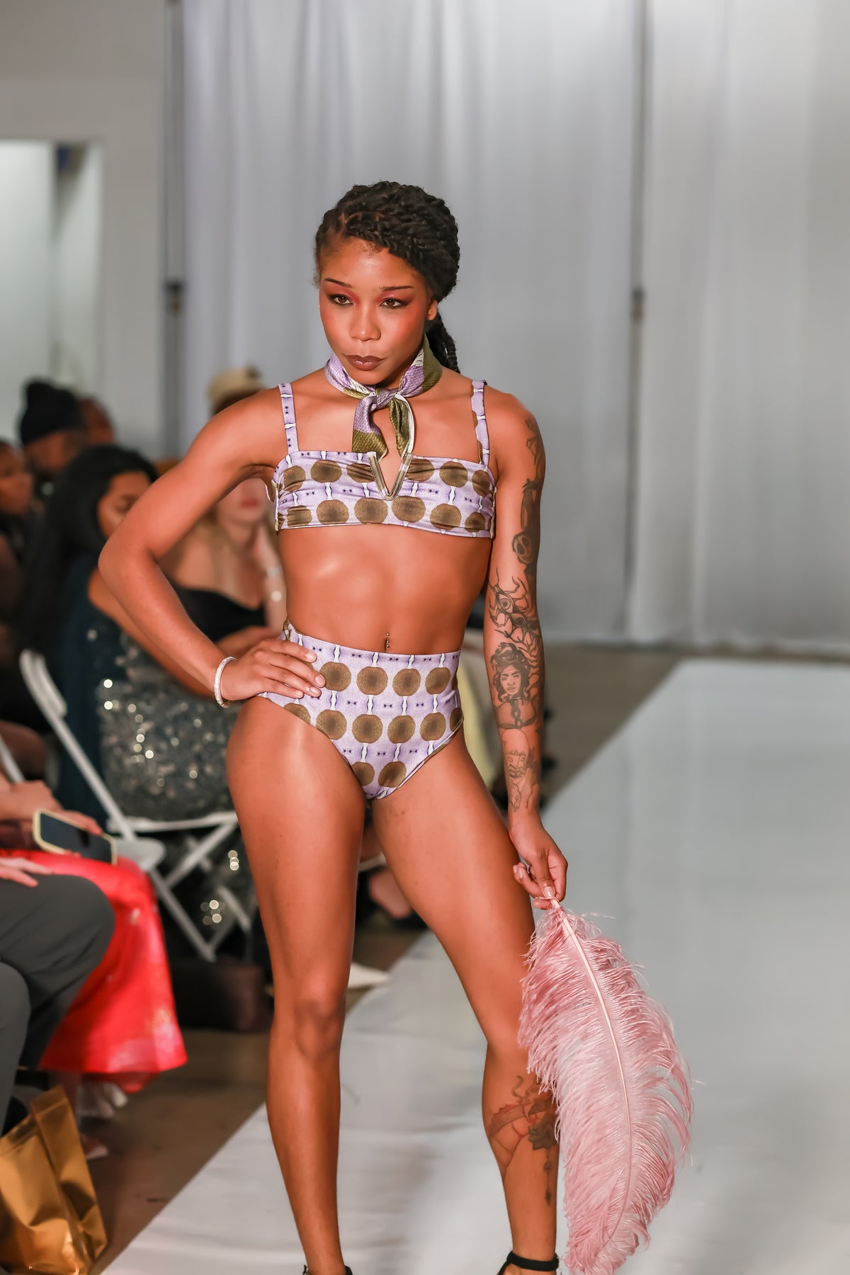 Front view of a model posing with a hand on her hip in a bralette bathing suit top with a lavender and brown medallion print, C. Monet Atelier