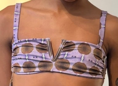 Close-up of a cutout bikini top with a V-notch bralette neckline and wide straps in a lavender and brown circle print