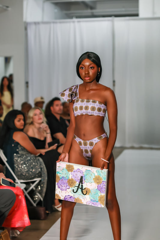 Model wearing a lavender print one shoulder bikini set on runway