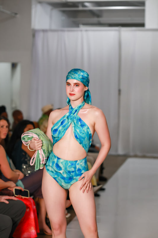 Model wearing the blue and turquoise Sky Cuore halter swimsuit with an open front and matching headscarf.