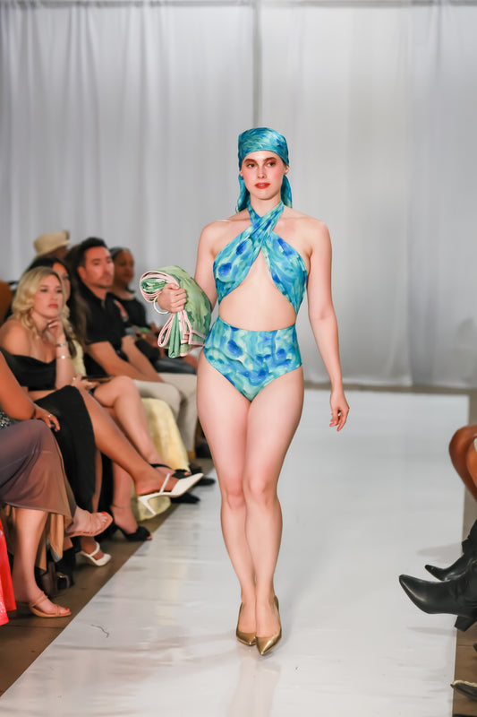 Full-length runway view of the Sky Cuore one-piece swimsuit with a cross-over halter neckline.