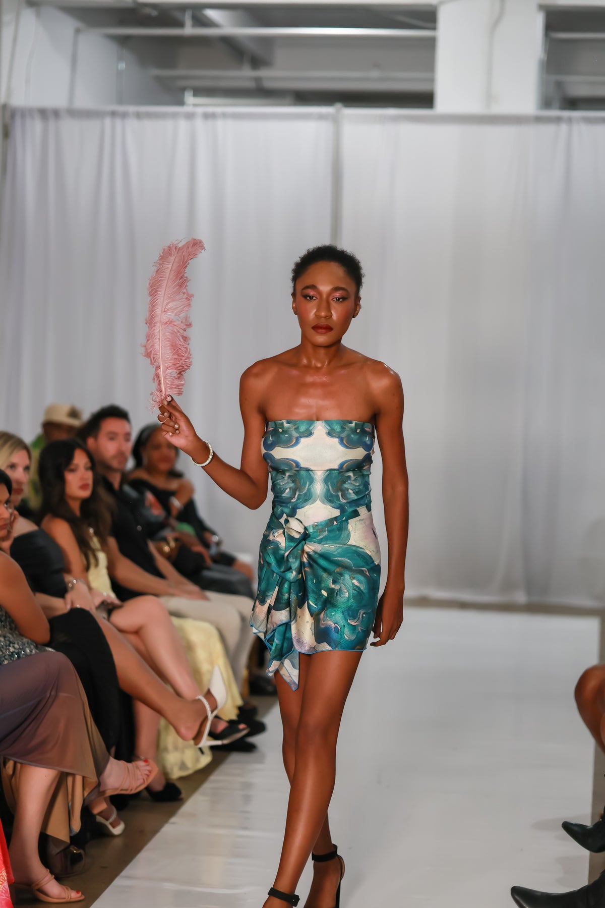 Strapless mini dress in blue abstract print styled with a pink feather accessory